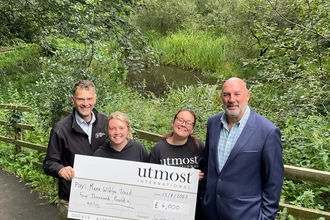 MWT CEO and Community Ranger stood with delegates from Utmost holding a large cheque for £4000 at Onchan Wetlands Nature Reserve