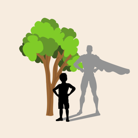 Image shows a boy stood next to a tree but his shadow is in the shape of superhero.