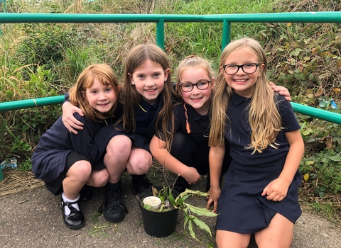 4 girls sat around a mini habitat they made in a plant pot